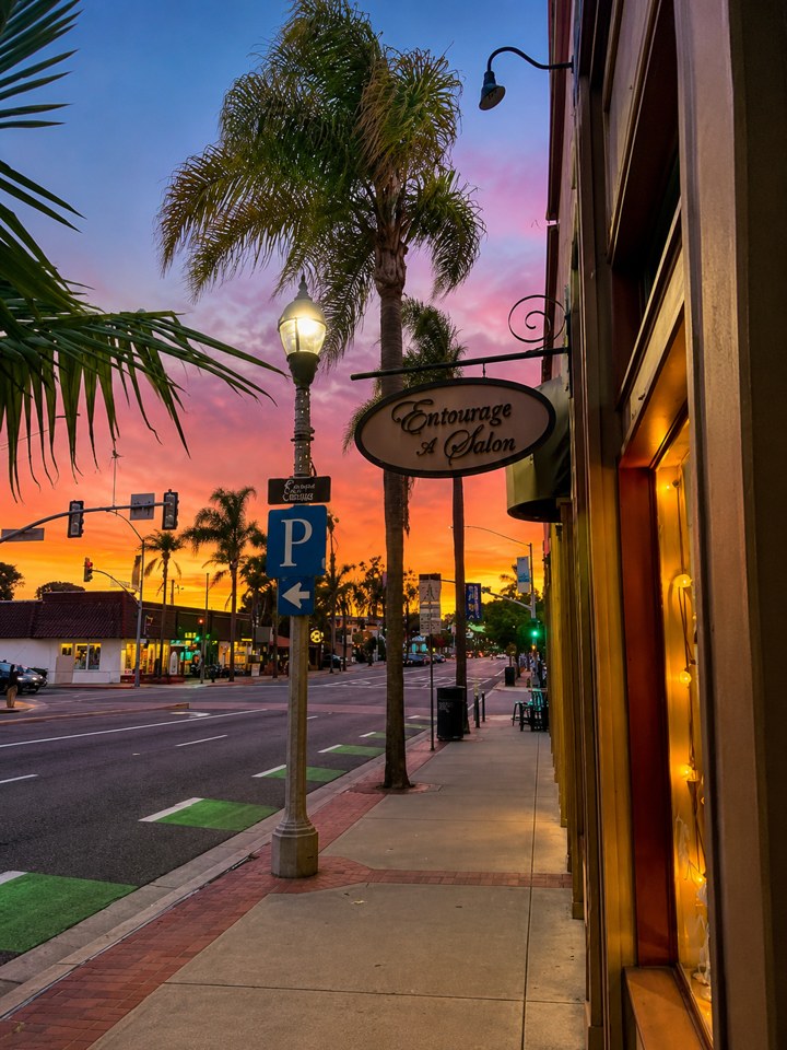Entourage Salon storefront on State Street in Carlsbad Village at sunset, with palm trees and the hanging Entourage — A Salon sign